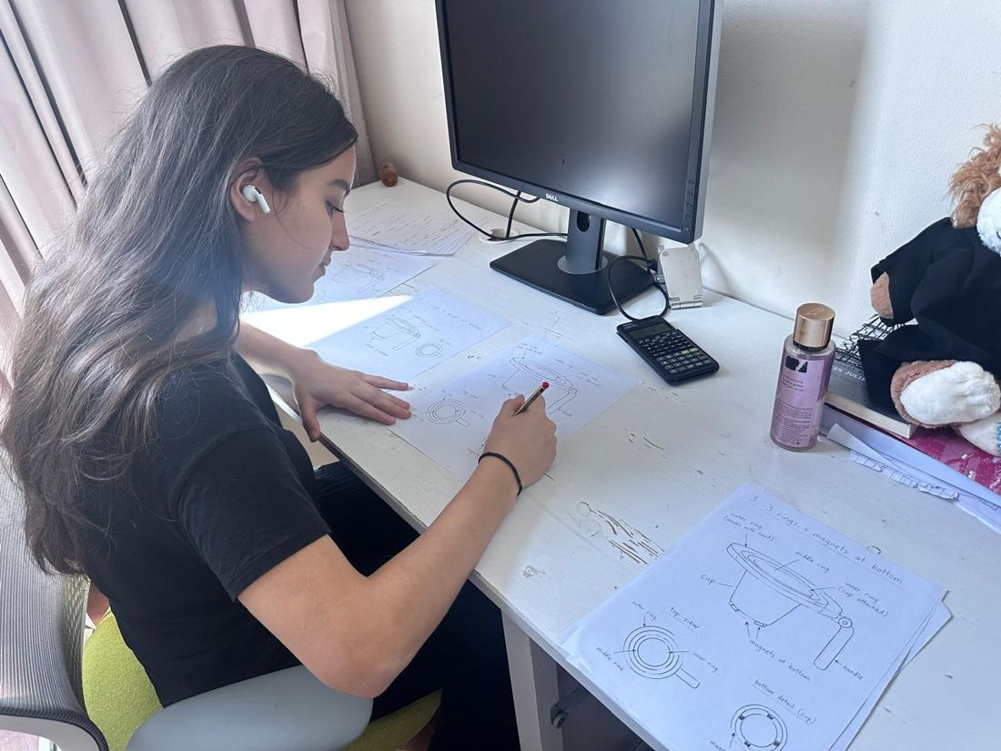 Selin drawing ParkiCup concept sketches at her desk.